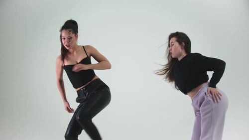 Zwei junge stilvolle Frauenmodels tanzen auf Cyclorama
