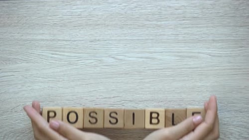 Possível, mãos empurrando palavra em cubos de madeira, possibilidades, motivação e objetivos