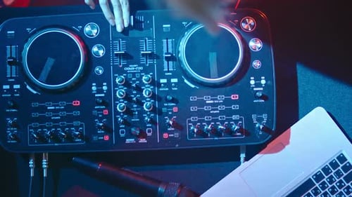 DJ Using Mixing Board, Laptop and Microphone
