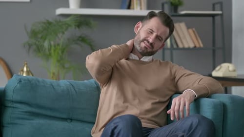 Man Rubbing Sore Neck on Couch