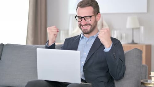 Man Celebrates Success While Using Laptop at Home