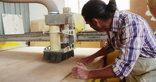 Carpenter using his machine and smiling for camera