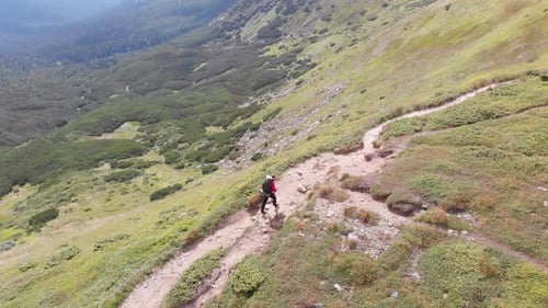 Aerial View of a Traveler with Backpack Climbing Along Mountain Slope. Epic Shot