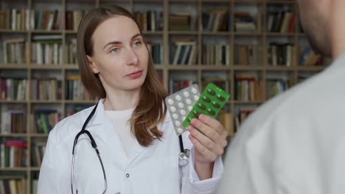 Female Doctor Gives Pills to a Male Patient in the Clinic