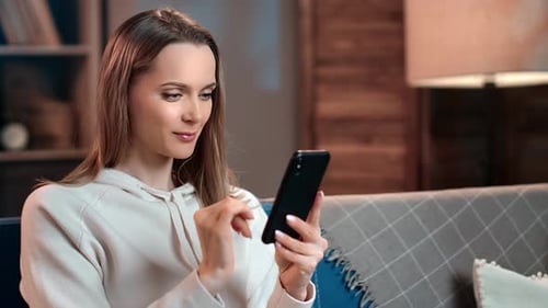 Woman Using Smartphone While Relaxing at Home