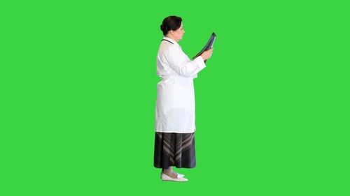 Reife Ärztin, die den Röntgenstrahl des Patienten auf einem Greenscreen-Chroma-Key untersucht