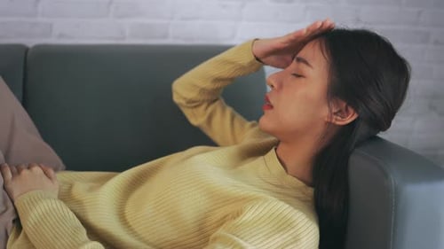 Young Woman Resting On Couch With Headache