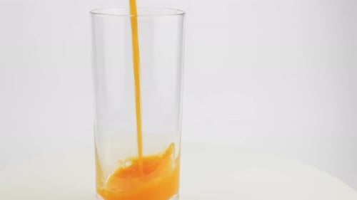 Orange Juice Being Poured Into Glass On White