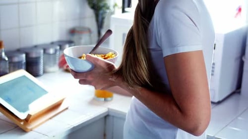 Woman using digital tablet while having breakfast