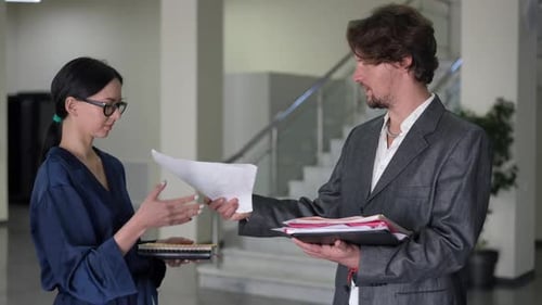 Employees Handing Over Documents in an Office Setting