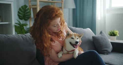 Woman Cuddles Shiba Inu Dog on Sofa