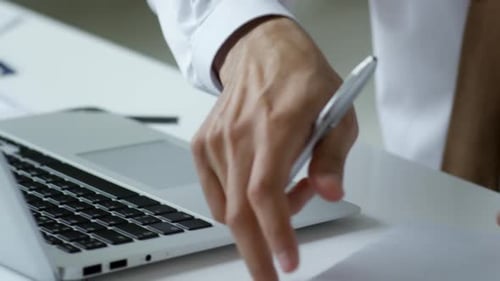 Close Up of Businessman Using Laptop and Writing in Arabic