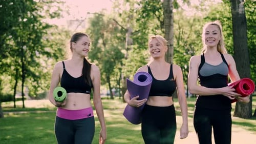 Fit Women Walking with Yoga Mats in Park