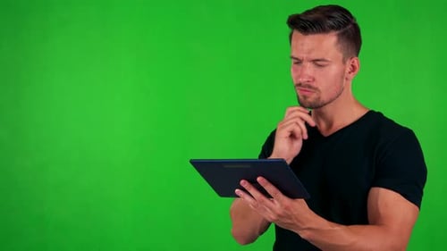 Young Handsome Caucasian Man Works on Tablet - Green Screen - Studio