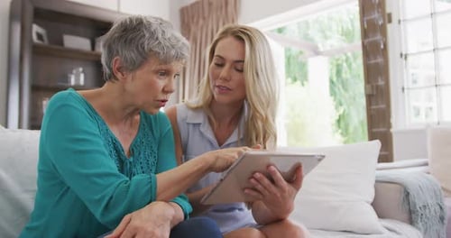 Senior Woman and Young Adult Using Tablet Together