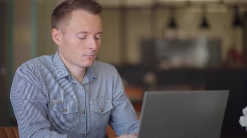 Focused Man Working on Laptop in Modern Office