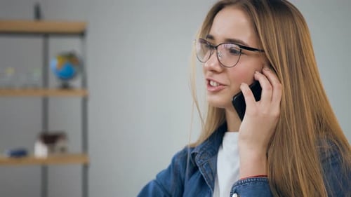 Hübsche junge Frau benutzt Smartphone im Reisebüro
