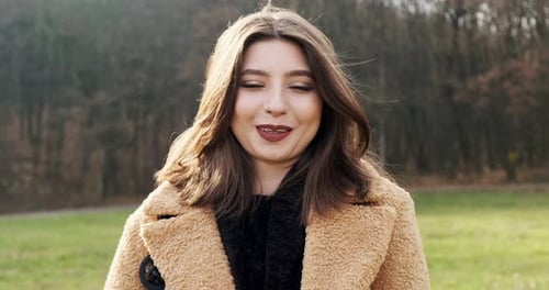 Porträt einer jungen attraktiven Frau, die auf grünem Rasen lächelt und in die Kamera schaut. Fröhlich