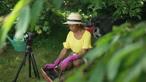 Side View Happy Confident African American Blogger Recording Video Sitting in Backyard Garden