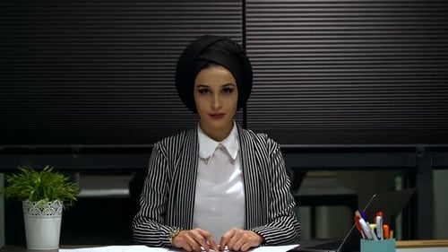 Junge Frau blickt im Büro in die Kamera