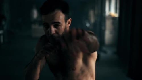 Shirtless Man Boxing and Training in Dark Room