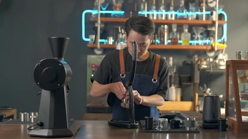 Young adult barista prepares espresso at cafe