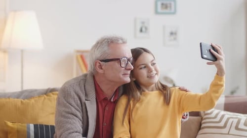 Grandfather and Granddaughter Taking Selfie at Home