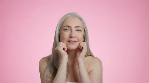 Smiling Senior Woman with Gray Hair Touches Face