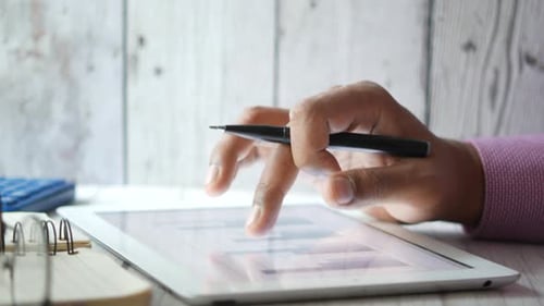 Man's Hand Working on Digital Tablet at Office Desk Using Self Created Chart