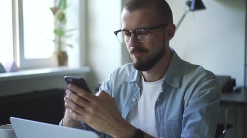 Man Using Smartphone While Working at Home