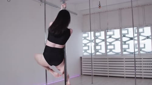 Pole Dancing in the Studio Brunette Slim Woman Spinning Around the Pole