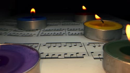 Colorful Tea Candles on Sheet Music