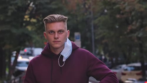 Young Adult Putting On Surgical Mask in City