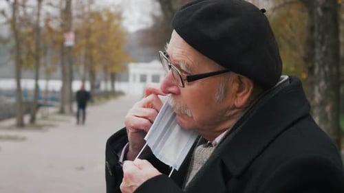 Senior Man Putting on a Protective Face Mask