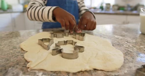 Child Cuts Dough With Cookie Cutters in Kitchen