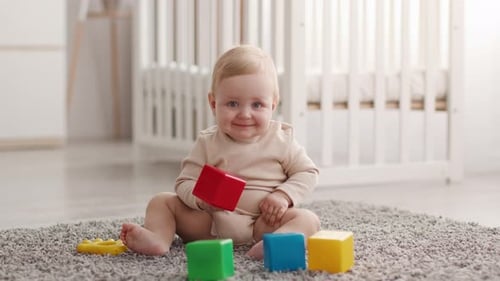 Smiling Baby Playing with Colorful Blocks on Rug