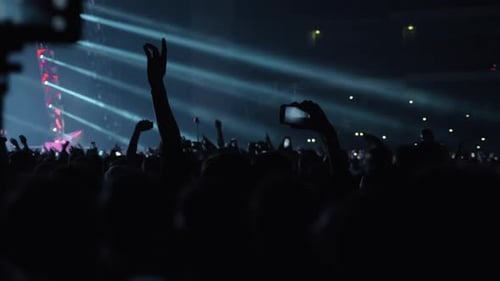 Silhouetted Crowd Enjoying Concert Under Bright Stage Lights
