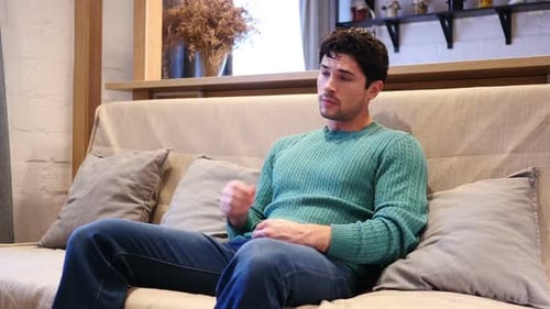 Yawning Tired Young Man Sitting on Couch at Home