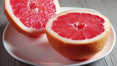 Juicy Grapefruit Halves on Plate with Water Droplets