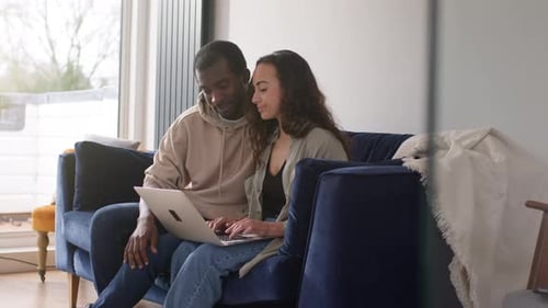 Woman Uses Laptop Sitting Next to Man on Couch