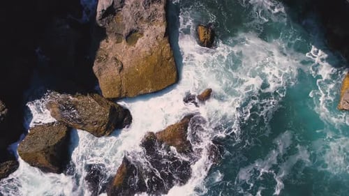 Drohnen-Drohnenansicht von tobenden Wellen, die an sonnigen Tagen an der bulgarischen Küste auf große Felsen stürzen