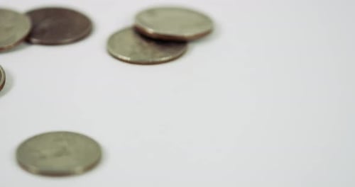Dropping Quarters Close Up on White Surface