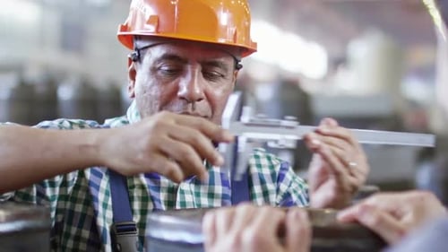 Worker Measuring Metal with Calipers in Factory Setting
