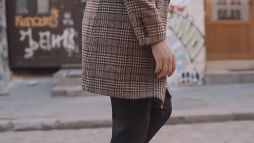 A man in a coat is walking down the street. Walk in the city center. Slow motion
