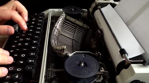 The man is typing on a retro typewriter.