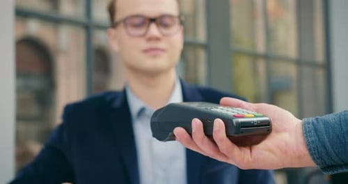 The Businessman Is Taking Out a Credit Card and Paying for the Order Via a Contactless Payment