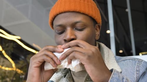 Young Adult Eating Burger at Indoor Restaurant