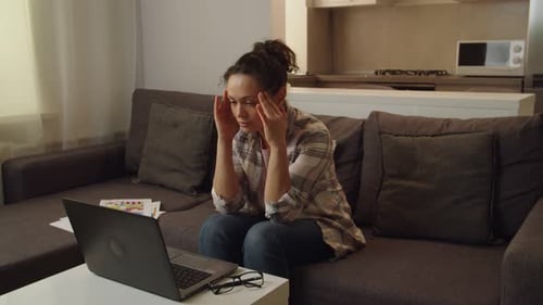 Woman Working On Laptop at Home Massages Temples