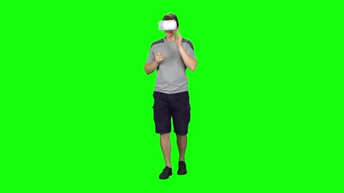 Smiling Man Wearing a Virtual Reality Headset Goes at the Green Screen