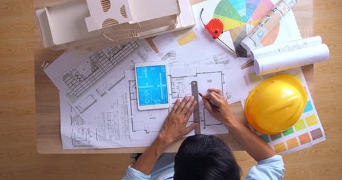 Draufsicht eines männlichen Architekten, der an einem Gebäudeentwurf mit einem Wohnmodellhaus arbeitet